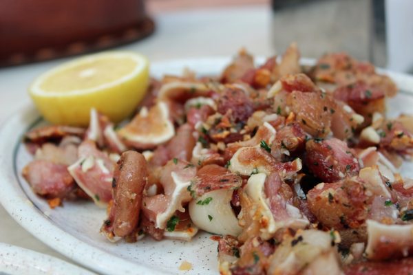 La oreja a la plancha, o oreja de cerdo frita, es uno de los platos típicos de Madrid. Aquí se sirve con tocino y un chorrito de limón encima. ¡Delicioso!